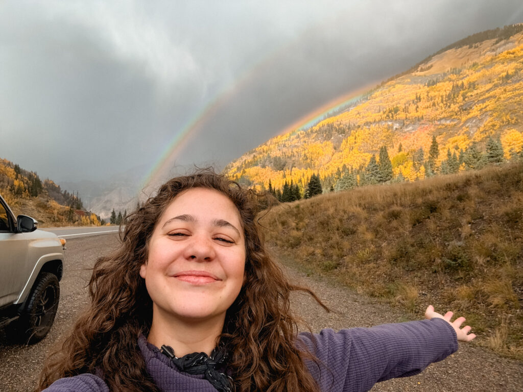 Mary Lee, owner of this website and photographer, selfie in front of a double rainbow in Colorado